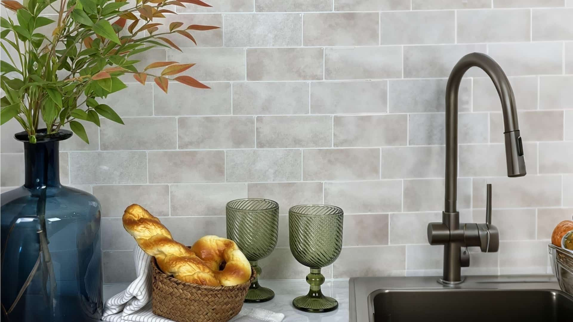 Stickwoll Tiles Verdant Dawn Subway Tiles in a kitchen setting with a sleek modern faucet, decorative plants, and fresh bread, creating a cozy and inviting atmosphere.