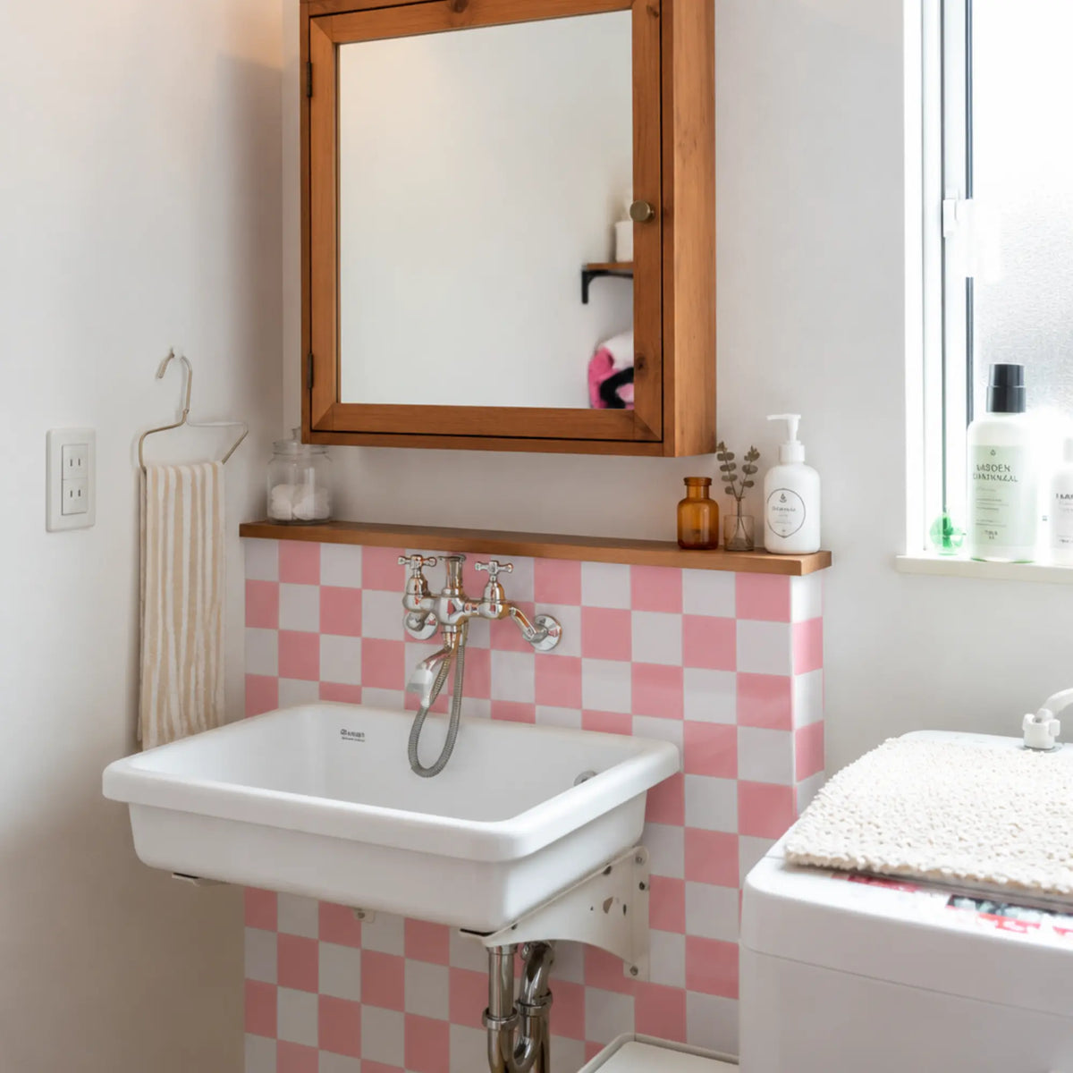 Small bathroom sink backsplash featuring Peach Shore pink and white checkerboard peel and stick wall tiles