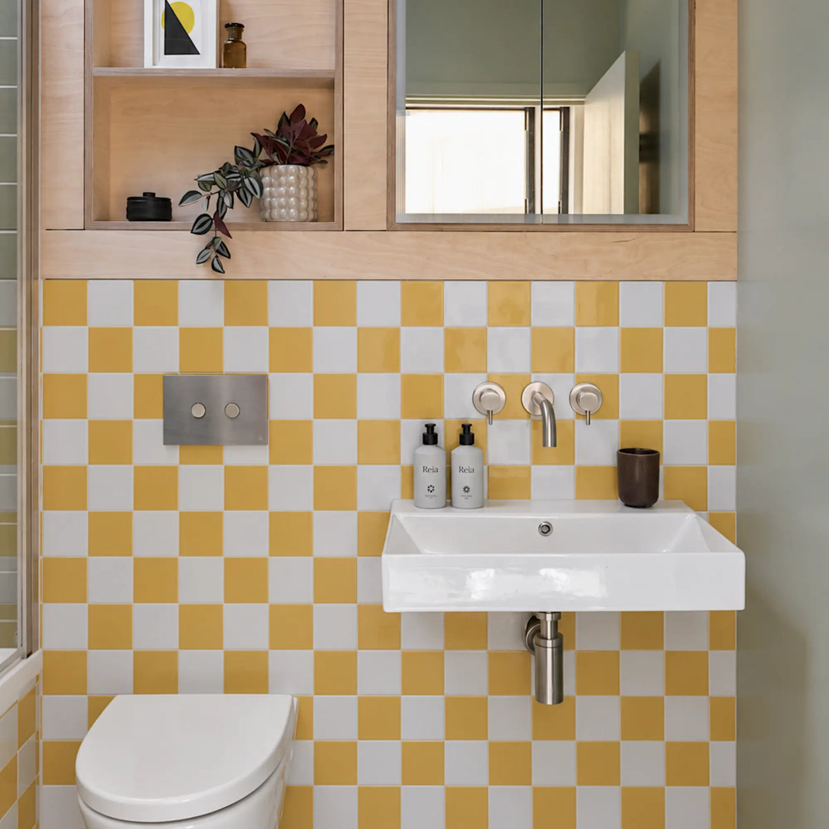 Bathroom wall makeover with Primrose Courtyard yellow and white checkerboard peel and stick tiles behind a pedestal sink