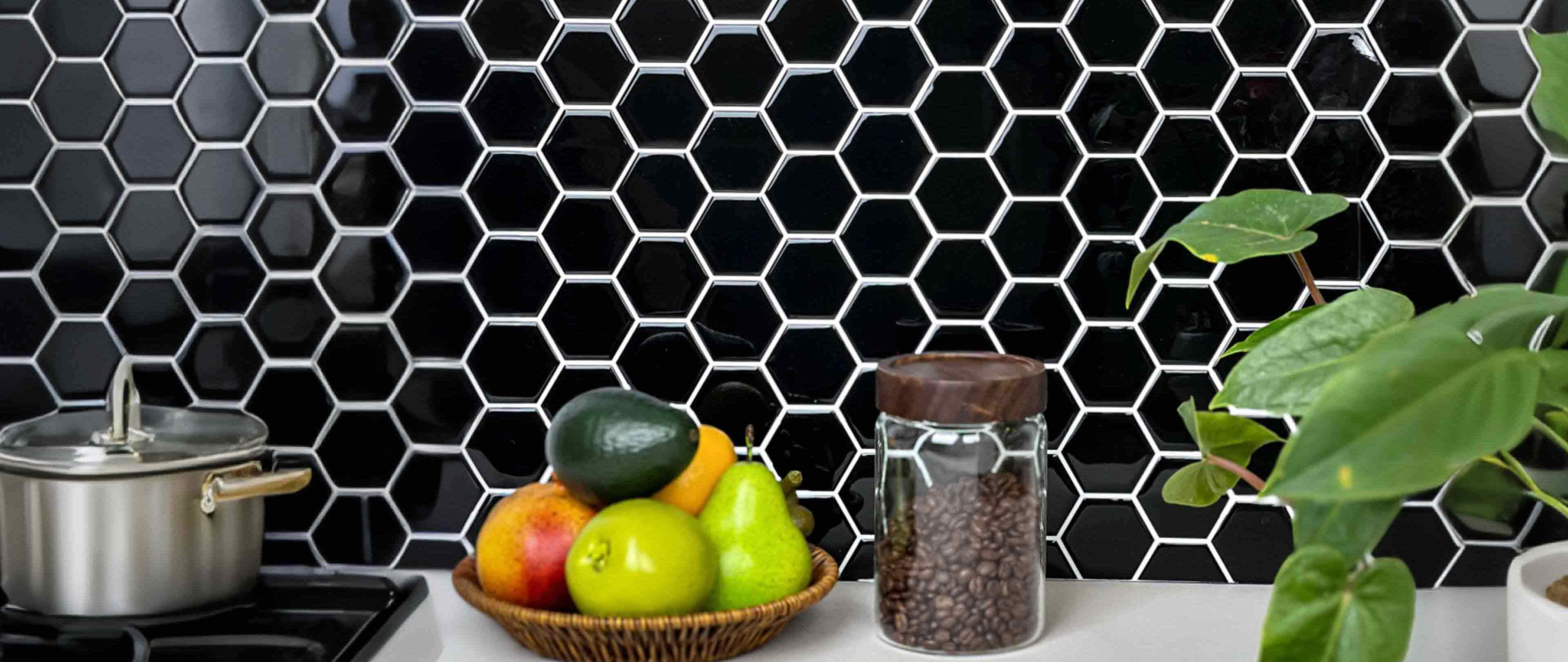 Stickwoll Peel and Stick Hexagon Tiles series showcased in a minimalist kitchen; featuring Onyx Hexagons Tiles on the wall, styled with a fruit bowl, coffee beans, and a green potted plant for a sleek and modern aesthetic