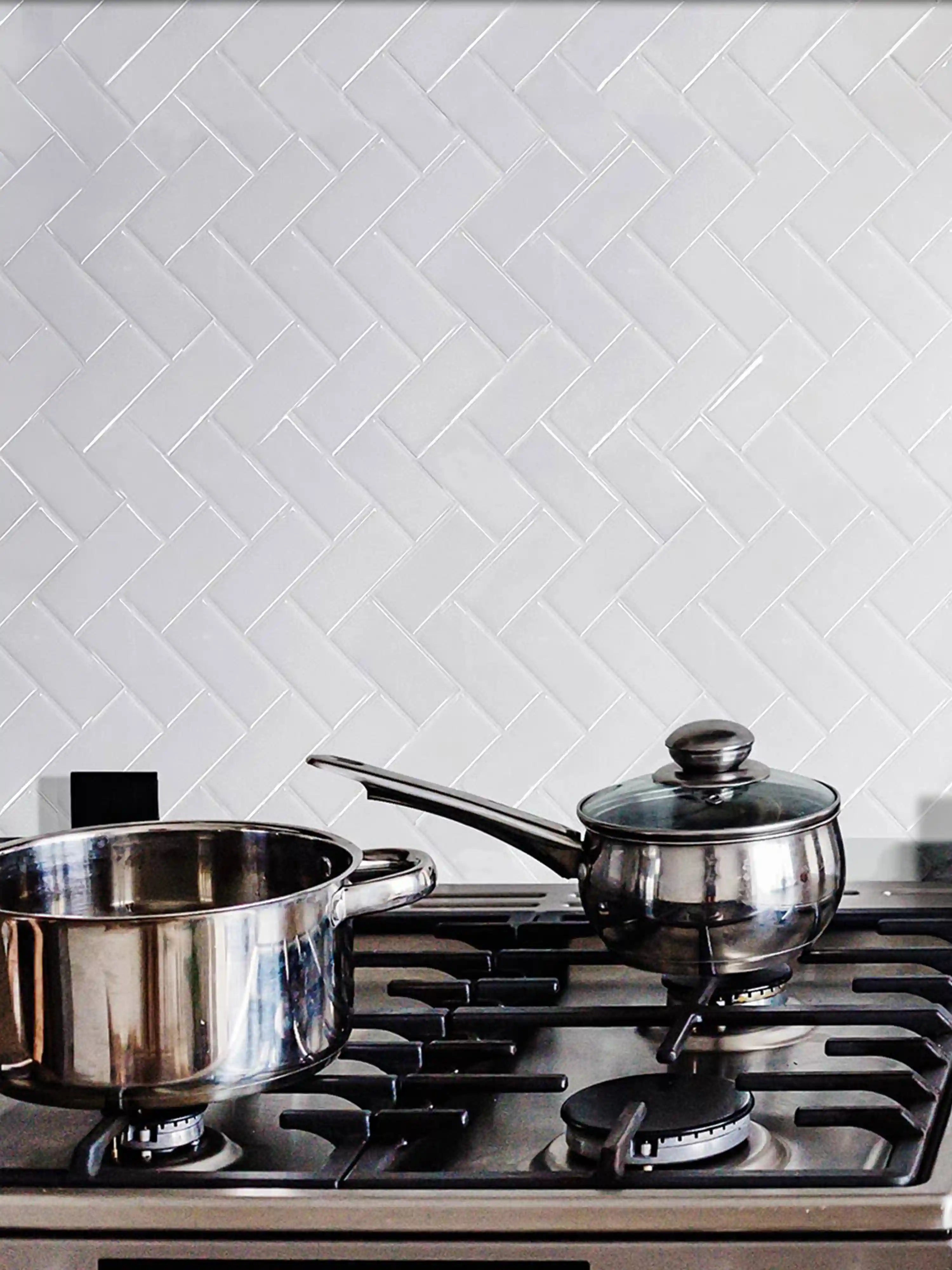 Stickwoll Peel and Stick Herringbone Tiles, featuring a classic Bright White Zigzag with a modern kitchen; displayed kitchen gas counter and pots and pans in a stylish and functional home setting