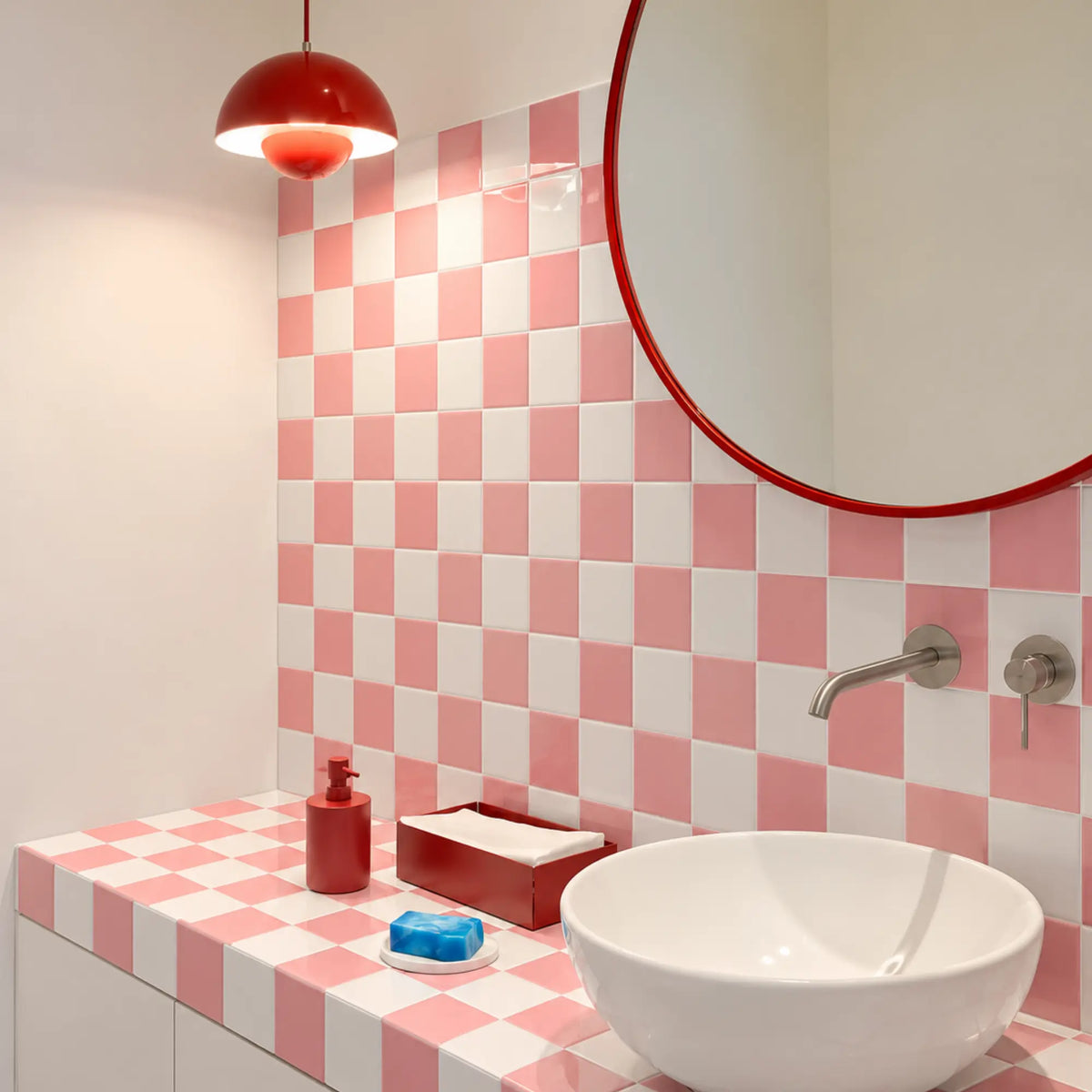 Playful bathroom with Peach Shore pink and white checkerboard peel and stick tiles around a round mirror and vessel sink