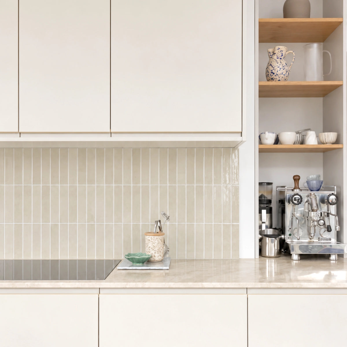 STICKWOLL Almond Elixir beige tiles used as a vertical kitchen backsplash with white cabinets and open wooden shelves.