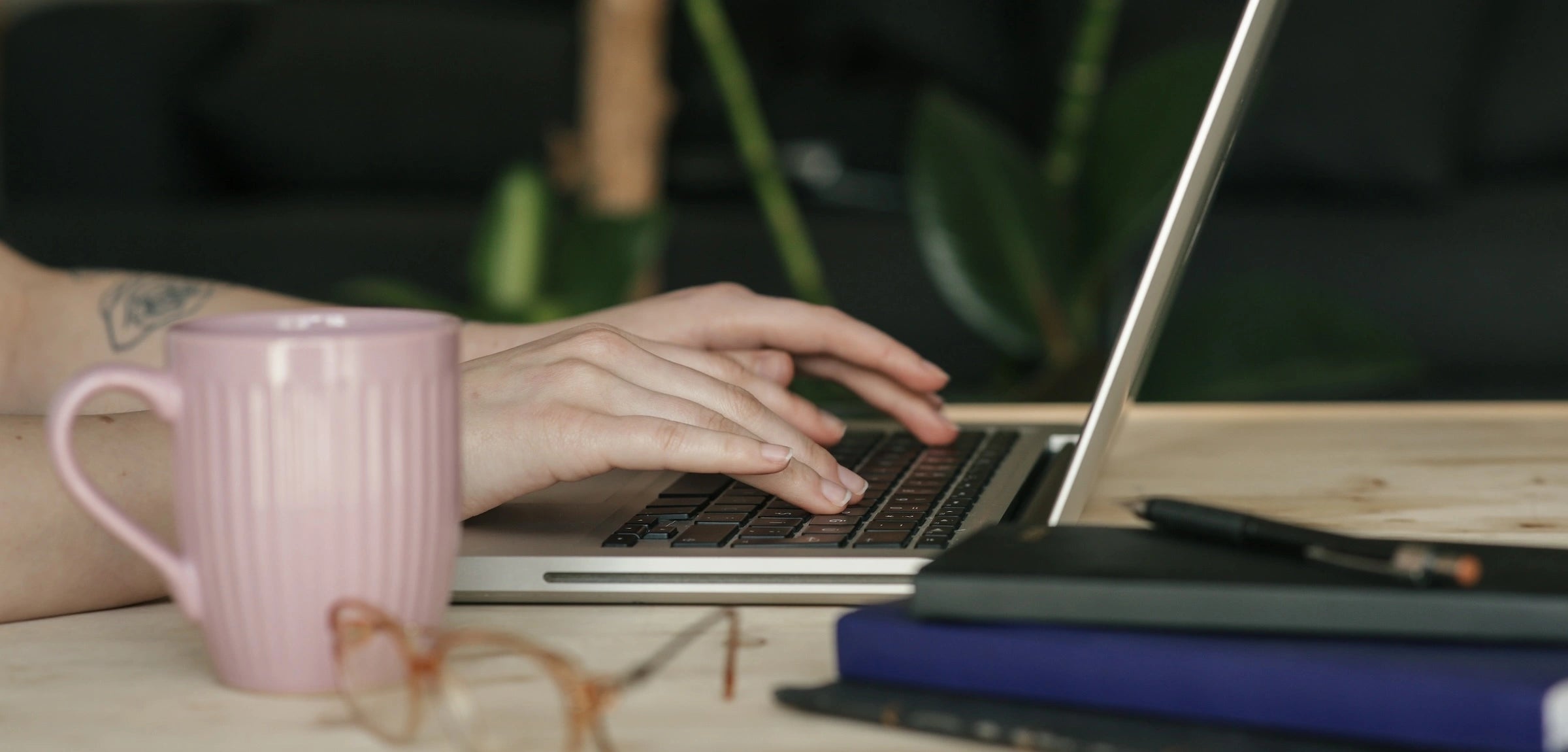 Close-up of hands typing on a laptop keyboard, sending a contact request through the Stickwoll website for inquiries or support